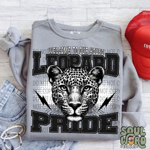 May include: Gray sweatshirt with a black and white leopard print design. The text "Welcome to our house Leopard Pride" is printed on the sweatshirt.