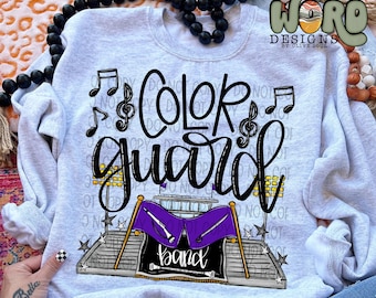 May include: A gray sweatshirt with the text "Color Guard" and a graphic of a marching band in a stadium. The graphic includes musical notes, flags, and the word "band".
