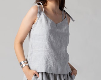 May include: A light gray linen skirt with a gathered waist and a matching linen tank top with thin straps. The model is wearing the outfit with brown suede flats.