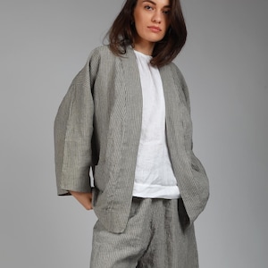 May include: A striped linen jacket and matching wide-leg pants in a gray and white color scheme. The jacket has a relaxed fit and a slightly cropped length. The pants have a high waist and a wide leg.