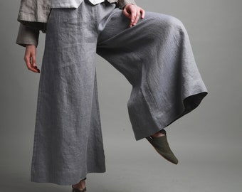 May include: Gray linen wide-leg pants with a loose, flowing fit. The pants have a high waist and are made of a lightweight, breathable fabric.