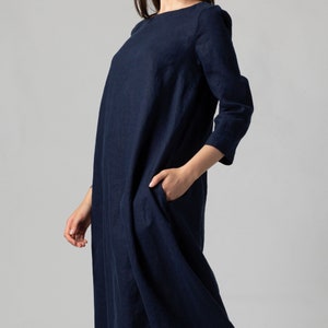 Minimalist maxi linen dress in Night Blue. Fitted in the upper part it flared generously down to the ankles. It features ¾ set in sleeves and side pockets. The wide optional belt offers various styling options.