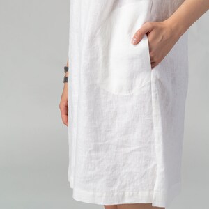 May include: A white linen dress with a single patch pocket on the left side.