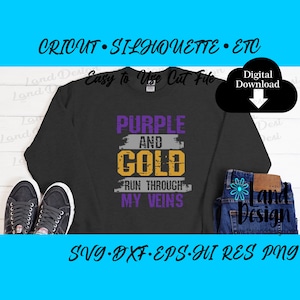 Könnte beinhalten: Lila und goldener Text auf einem grauen Sweatshirt mit den Worten "Run through my veins". Der Text ist im Used-Look gehalten und in Lila und Gold gehalten. Das Sweatshirt liegt auf einer weißen Oberfläche mit einem Paar schwarzen Turnschuhen und einer blauen Jeans.
