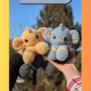 May include: Two handmade plush toys, one yellow and one blue, resembling a cartoon character. The toys have large ears, round eyes, and are held up against a blue sky. The text "SHINX PATTERN" is at the top.