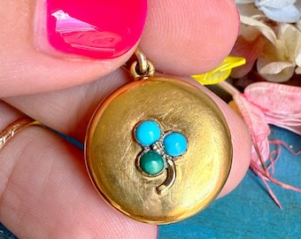 May include: A gold locket with a clover design featuring three turquoise stones and a smaller green stone in the center.
