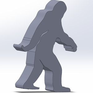 May include: A gray 3D printed model of a Bigfoot or Sasquatch walking. The model is printed in a solid gray color and has a detailed design.