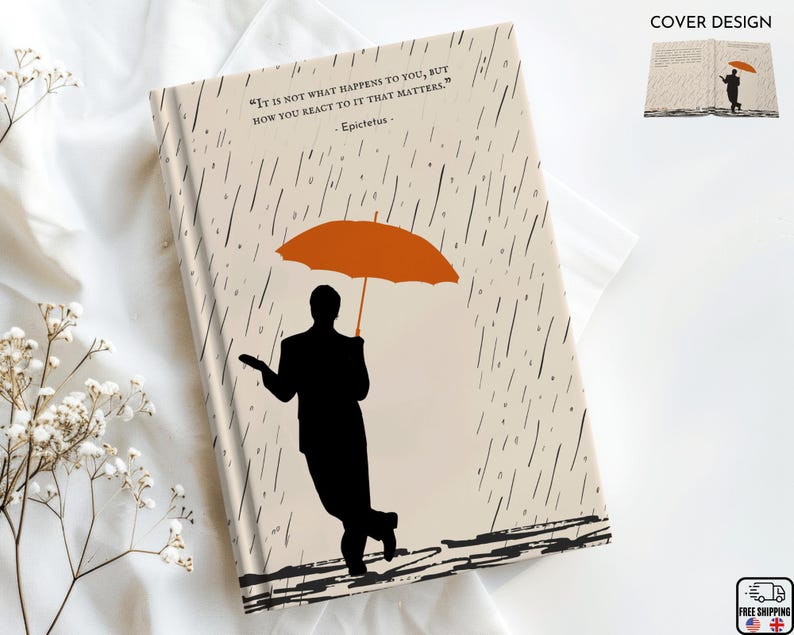 May include: A beige journal cover with a black silhouette of a person holding an orange umbrella. The background is a pattern of black rain drops. The quote "It is not what happens to you, but how you react to it that matters." by Epictetus is printed on the cover.