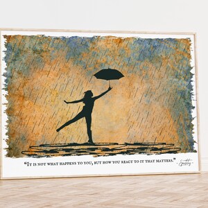 Könnte beinhalten: Gerahmter Kunstdruck mit einer Silhouette einer Person mit einem Regenschirm im Regen. Der Hintergrund hat Aquarell-Waschungen in Blau und Orange. Das Zitat "It is not what happens to you, but how you react to it that matters." ist unten gedruckt.