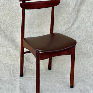 May include: A dark brown wooden chair with a curved back and a padded seat. The chair has a simple design with a single horizontal slat across the back.