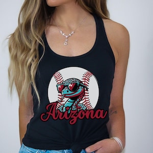 May include: Black tank top featuring a cartoon snake wearing heart-shaped sunglasses, set against a baseball. The word "Arizona" is written in a cursive font below the graphic. The tank top is tied at the waist.