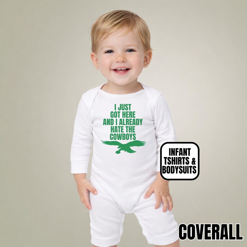 Puede incluir: Un body blanco de manga larga para beb&eacute; con texto verde que dice I JUST GOT HERE AND I ALREADY HATE THE COWBOYS sobre un gr&aacute;fico de &aacute;guila verde. La prenda incluye una peque&ntilde;a etiqueta rectangular con el texto INFANT TSHIRTS & BODYSUITS.