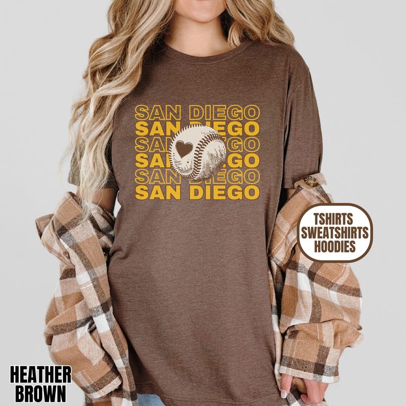 May include: Brown t-shirt with the text "SAN DIEGO" repeated in a retro style with a baseball and heart graphic. The text is in yellow and the graphic is in white.