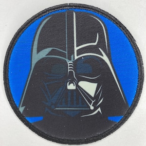 Puede incluir: Un parche redondo negro y azul con una imagen en blanco y negro de la cara de Darth Vader.