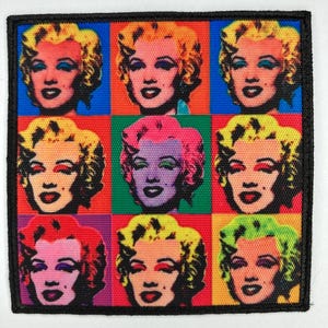 Könnte beinhalten: Quadratischer Aufnäher mit einem Pop-Art-Design von Marilyn Monroes Gesicht in einem Rastermuster. Jedes Quadrat hat einen anderen Hintergrund in leuchtenden Farben, mit Variationen in Haar- und Make-up-Farben. Der Aufnäher hat einen schwarzen Rand.