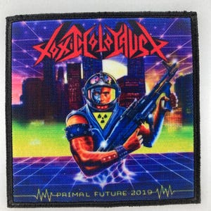 Op de afbeelding: Vierkante patch met een futuristisch ontwerp. De patch toont een figuur in een blauw uniform met een wapen, tegen een stadsgezicht en een rasterpatroon. De tekst "Xenocide" staat bovenaan, met "Primal Future 2019" onderaan.