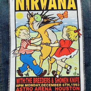 May include: A rectangular fabric patch featuring a Nirvana concert poster graphic. The design shows two children dancing with a stylized creature under the text NIRVANA. Below, text reads WITH: THE BREEDERS & SHONEN KNIFE 8PM MONDAY, DECEMBER 6TH, 1993 ASTRO ARENA HOUSTON.