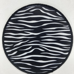 Puede incluir: Un parche de tela con estampado de cebra en blanco y negro con un borde cosido negro.