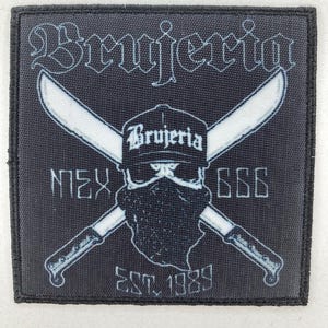 Puede incluir: Parche cuadrado negro con la palabra "Brujeria" en letras blancas estilizadas. El diseño incluye cuchillos blancos cruzados, una calavera con una gorra con "Brujeria" y los textos "MEX" y "666". El parche también tiene "EST. 1989".
