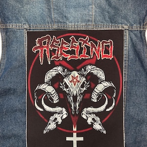May include: A black and red patch with the word "RESINO" in red lettering. The patch features a skull with horns and a pentagram inside a circle. A cross is at the bottom of the patch.