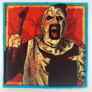 May include: A square fabric patch featuring a graphic illustration of a clown with a white face, black eyes, and a wide open mouth. The clown is splattered with red blood and holds a brown axe. The background is red, framed by a bright blue border.