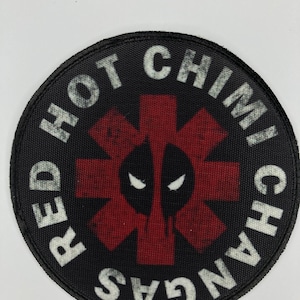 May include: A black and red round patch with the text "RED HOT CHILI PEPPERS" in white around the edge. A red medical symbol with a black Deadpool face is in the center.