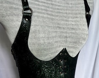 May include: A black leather corset with an intricate floral pattern and adjustable straps. The corset has a lace-up back and is made of high-quality leather.