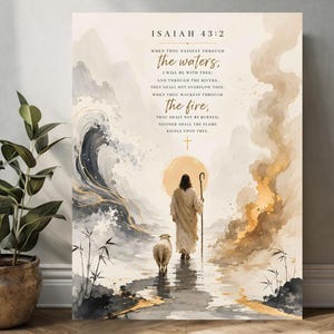May include: A rectangular wall art print featuring a figure in robes holding a staff, walking with a sheep toward a golden sun. The artwork includes the text Isaiah 43:2 and the verse about passing through waters and fire, with watercolor-style imagery of swirling blue waves and golden flames.