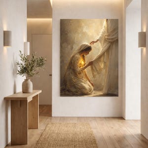 May include: A vertical wall art print depicting a kneeling figure in a light-colored robe reaching out to touch the hem of a standing figure draped in flowing white fabric. The scene is rendered in warm, golden tones with a soft, ethereal glow.