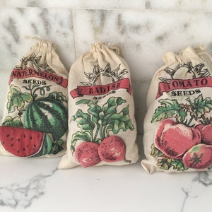 May include: Three white fabric bags with red, green, and black printed designs. The bags are labeled "Watermelon Seeds", "Radish Seeds", and "Tomato Seeds".
