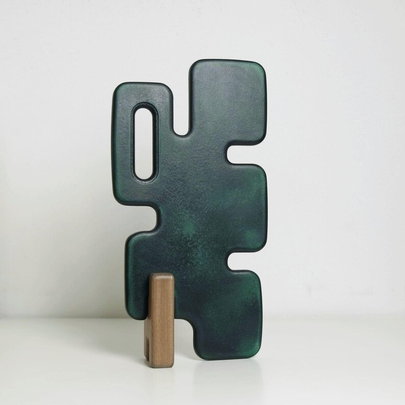 modern decorative object consisting on two elements. A larger, black element that fits into a smaller one made of mahogany, which acts as a support that allows the sculpture to stand