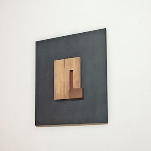 wall art sculpture crafted out of black dyed recycled boards and carved wood geometric elements