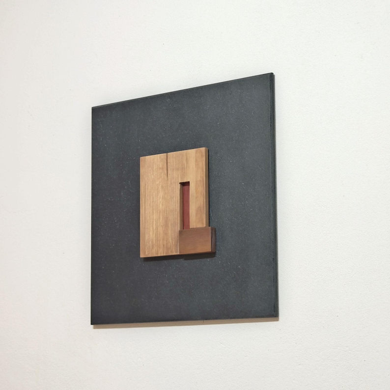 wall art sculpture crafted out of black dyed recycled boards and carved wood geometric elements