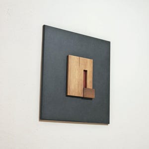 black and multiple wood tones artwork hanging on a white wall