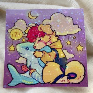 May include: A square holographic sticker featuring a cartoon illustration of a yellow dog with pink hair hugging a blue shark plush. The background is a purple night sky with clouds, a crescent moon, hanging stars, and a yellow circle with ZZZ text.