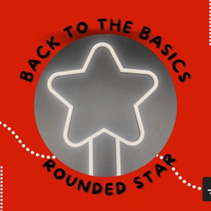 May include: Back to the basics: rounded star. A white neon star with rounded edges is displayed on a gray background. The text "Back to the basics" is written in black around the star, and the text "rounded star" is written in black below the star.