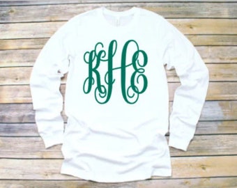 May include: White long-sleeve t-shirt with a green monogram of the letters "RJC" in a cursive font.