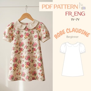 Peut inclure: Une robe à imprimé floral avec un col Claudine et des manches courtes bouffantes est suspendue à un cintre en bois. La robe présente un fond beige avec des roses roses et jaunes. Le texte sur l'image indique "PDF PATTERN FR_ENG 1Y-7Y ROBE CLAUDINE Beginner".