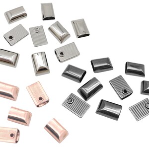 May include: Assortment of metal end caps in silver, black, and rose gold. The end caps are rectangular and have a smooth, polished finish.