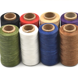 Può includere: Otto bobine di filo cerato in vari colori, tra cui verde, bianco, blu, marrone, viola, beige, rosso e nero. Le bobine sono disposte in fila su uno sfondo bianco.