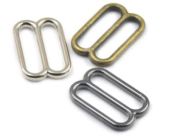 May include: Three metal slider buckles in different finishes: silver, antique brass, and black nickel. Each buckle has two loops.