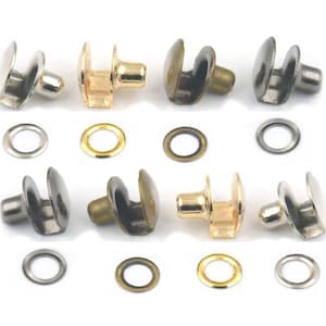 Op de afbeelding: Assortiment van metalen oogjes en klinknagels in zilver, goud en messing afwerkingen. De oogjes zijn rond en hebben een gladde afwerking. De klinknagels hebben een ronde kop en een puntige schacht.