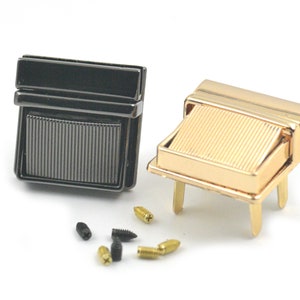 Pode incluir: Dois fechos metálicos, um dourado e outro preto, com um design nervurado. Os fechos são usados para prender bolsas ou carteiras.