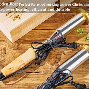K&ouml;nnte beinhalten: Zwei Holzbrennwerkzeuge mit Holzgriffen und schwarzen Kabeln. Die Werkzeuge befinden sich auf einer Holzoberfl&auml;che. Der Text "HAND CRAFTED" und "Lody Pas" ist auf einer Holzkiste im Hintergrund sichtbar.