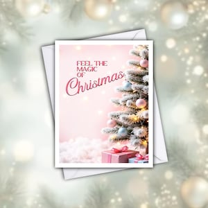 May include: A rectangular greeting card featuring a frosted Christmas tree decorated with pink and blue ornaments. The text "FEEL THE MAGIC OF Christmas" is printed in pink. Two wrapped gift boxes sit at the base of the tree on a snowy surface.