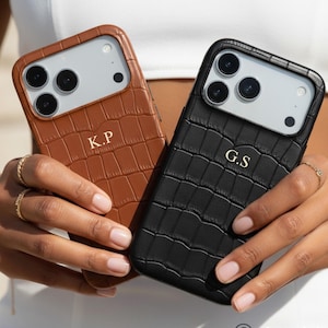 Puede incluir: Se muestran dos fundas para tel&eacute;fono, una marr&oacute;n y otra negra. Ambas fundas tienen una textura de piel de cocodrilo e iniciales doradas. La funda marr&oacute;n tiene las iniciales "K.P" y la funda negra "G.S".
