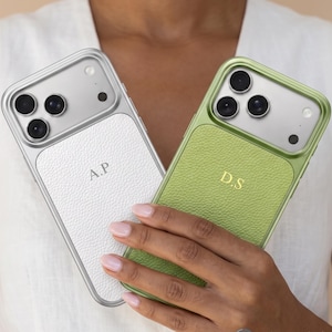 Puede incluir: Dos fundas para smartphone con paneles traseros de textura similar al cuero y marcos metálicos. Una funda es blanca con las iniciales A.P. en plata, y la otra es verde lima con las iniciales D.S. en oro. Ambas tienen recortes para triple cámara.