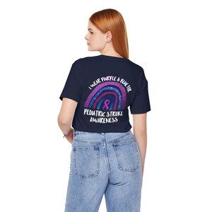 Peut inclure: Un t-shirt bleu marine avec un motif arc-en-ciel et le texte "Je porte du violet et du bleu pour la sensibilisation aux accidents vasculaires cérébraux pédiatriques".