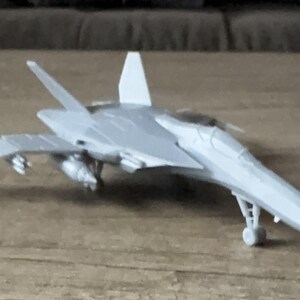 Puede incluir: Un modelo de avi&oacute;n gris con un dise&ntilde;o elegante, con alas, cola y tren de aterrizaje. El avi&oacute;n de juguete es una r&eacute;plica en miniatura de un caza a reacci&oacute;n, que muestra detalles.