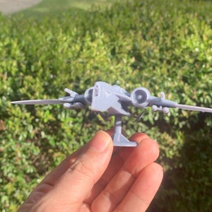 Pode incluir: Um modelo de nave espacial de pl&aacute;stico cinza com dois motores e um suporte. A nave espacial tem um nariz pontudo e duas asas.